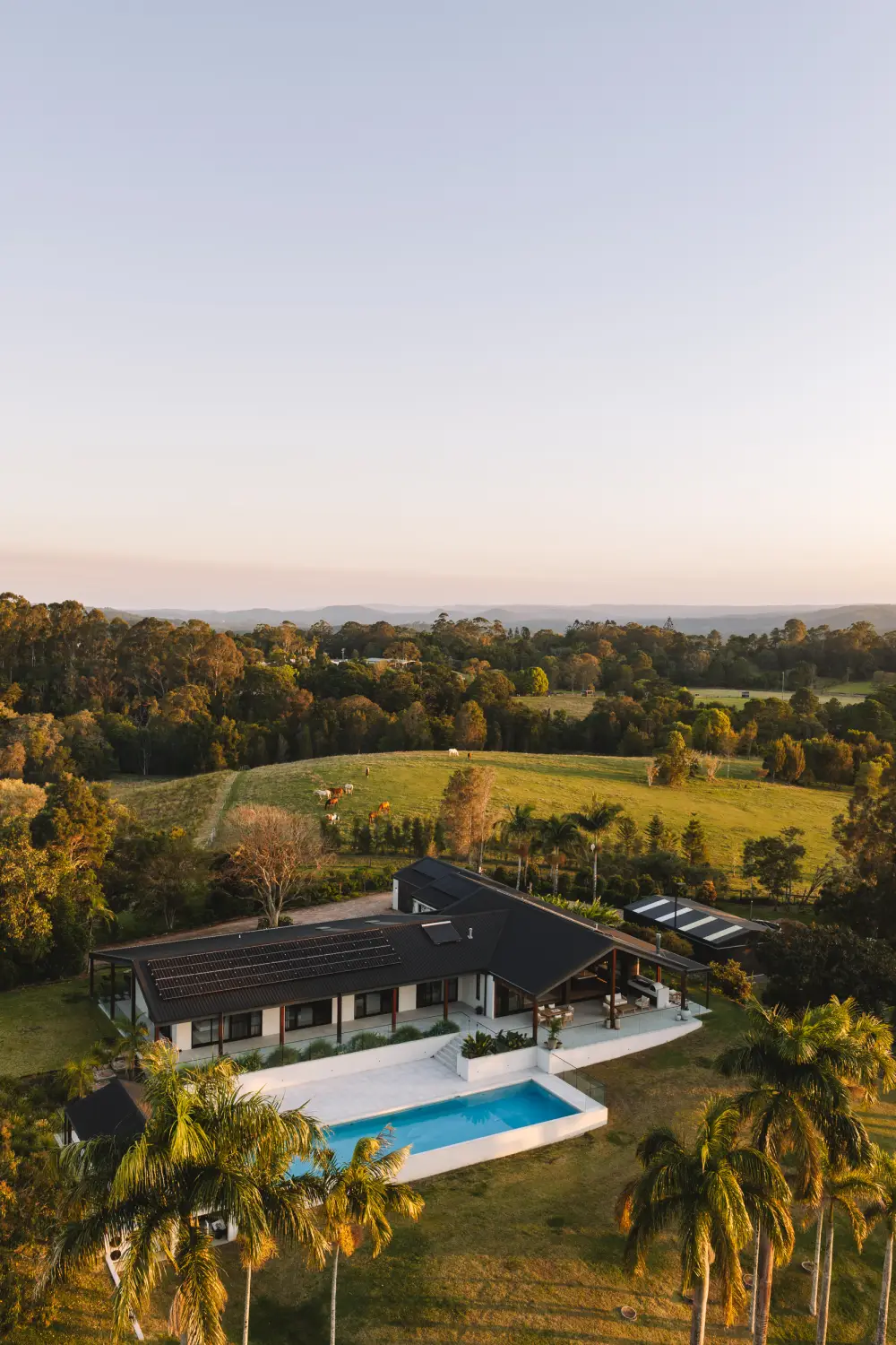 An aerial photograph of a house, pool and paddocks at dusk