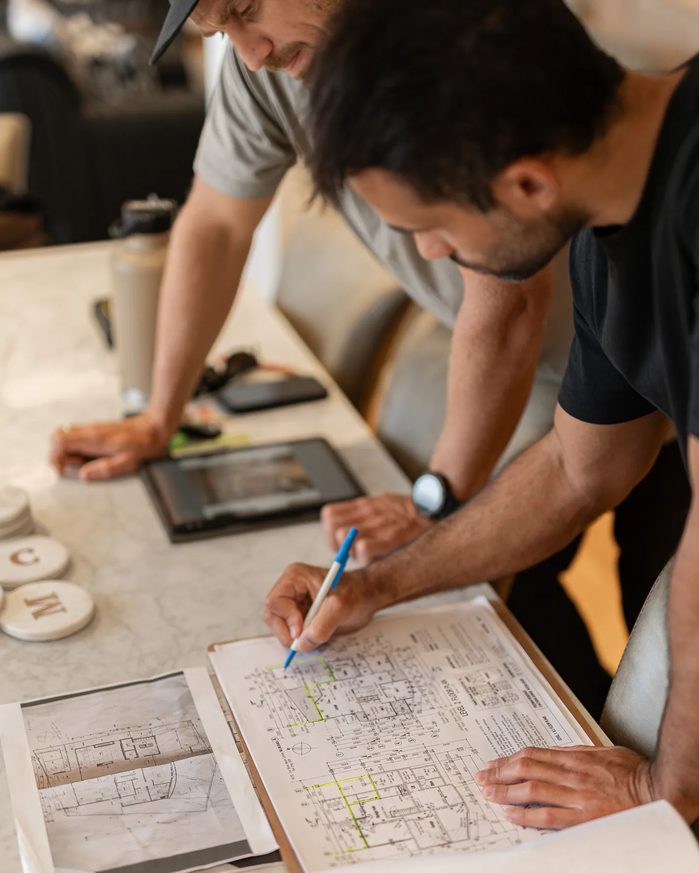 Two people marking up a set of plans on a table