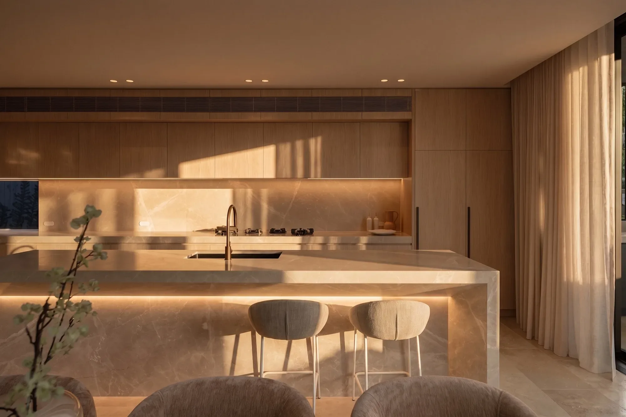A stone kitchen bench in warm late sunlight, timber joinery behind