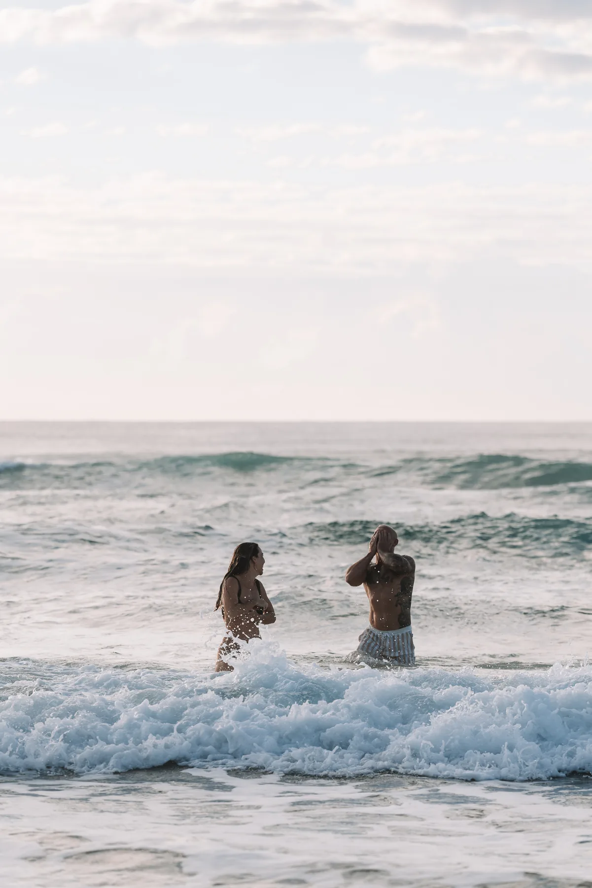 Two people walking out of the surf in the late afternoon