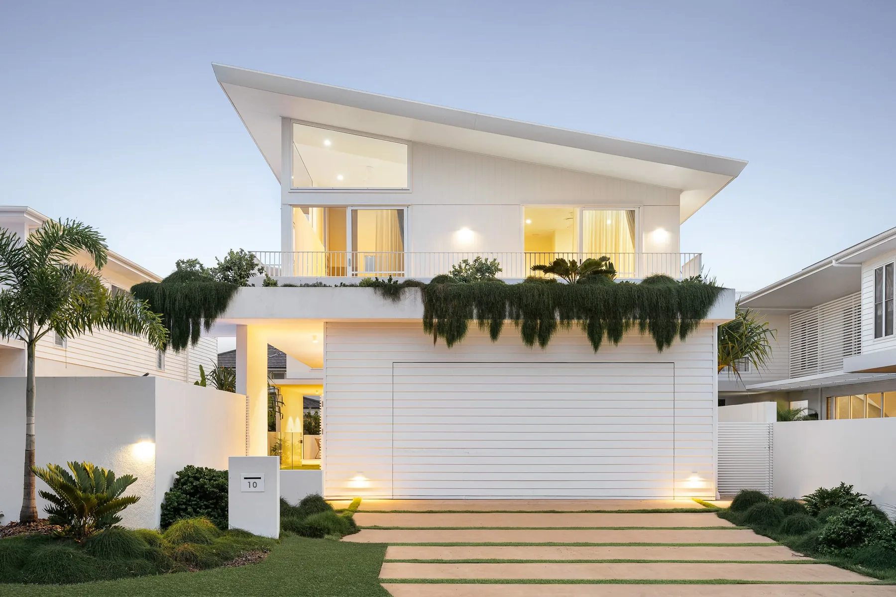 A white two-storey house photographed from the street at twilight